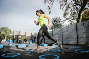 femme-en-debardeur-vert-et-leggings-noirs-faisant-du-yoga-sur-trampoline-rond-bleu-YxCrQm9XNgg